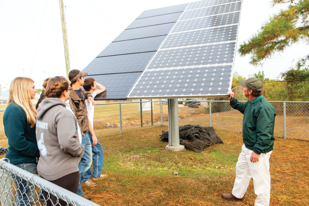 Instructor Barry Bey talks with students about the solar panel array, which powers pumps and aerators for the ponds at South Brunswick High School in Southport. 