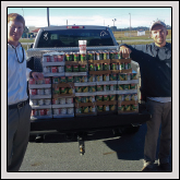 Taylor Ginn, left, and John Bledsoe, right, both of AgCarolina, receive a canned food donation from Lenoir County YF&R member Brent Herring, center.