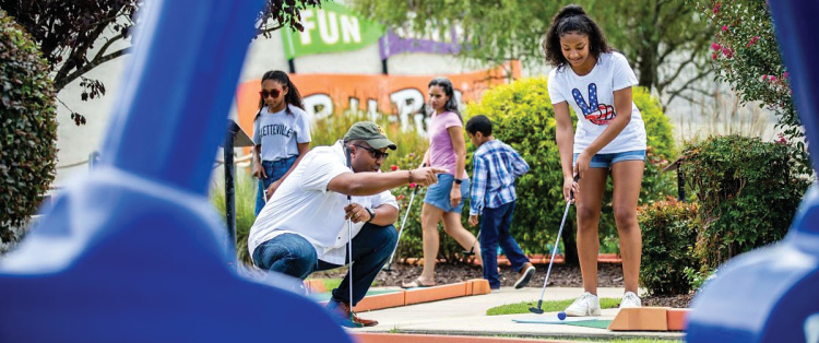 Families play putt-putt golf at the Putt-Putt Fun Center