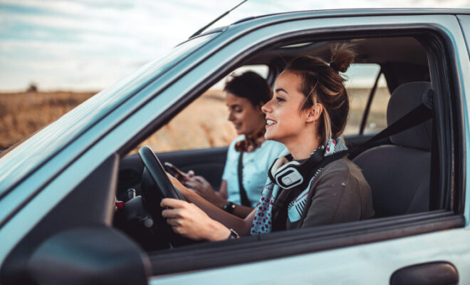 Beautiful twin sisters driving a car and enjoying summer road trip